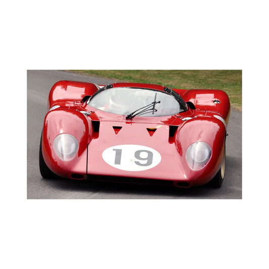 Red vintage racing car number 19 on asphalt track with driver inside helmet