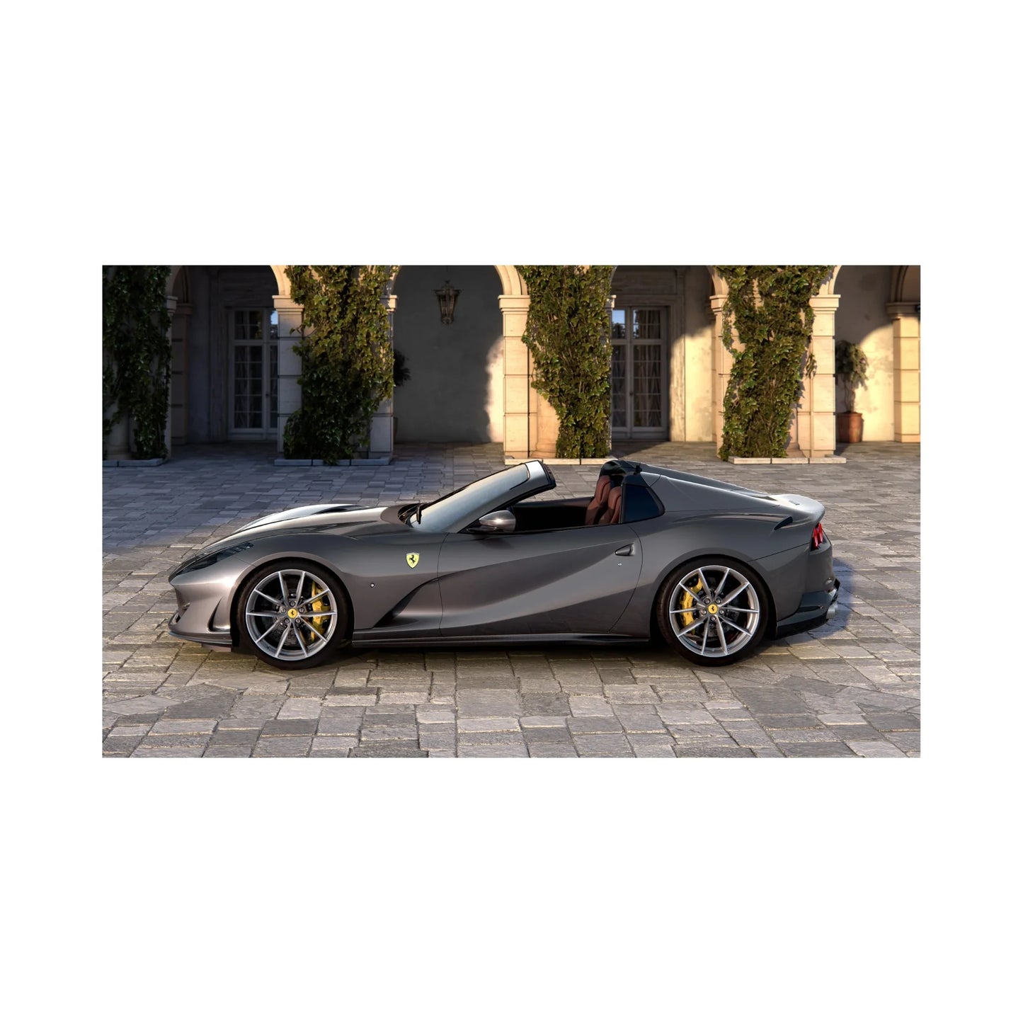 Gray Ferrari convertible sports car parked on stone driveway with ivy-covered arches in background