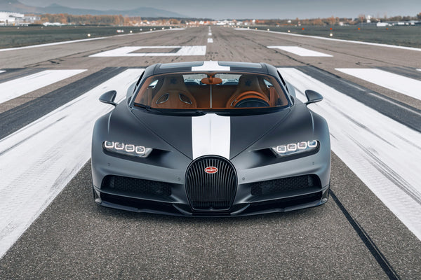 Matte black Bugatti Chiron Sport with white stripe on airport runway, luxury sports car front view