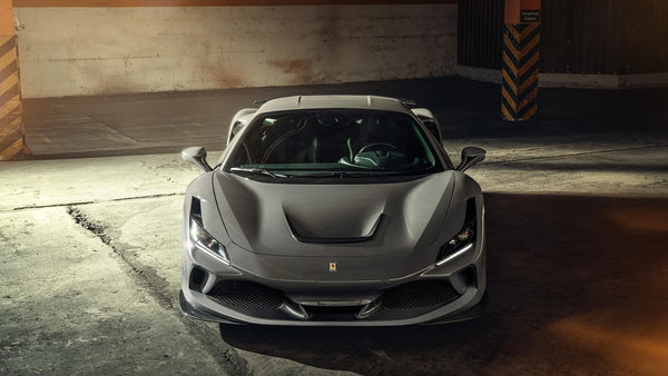 Front view of a sleek matte gray Ferrari F8 Tributo sports car in a dimly lit industrial garage