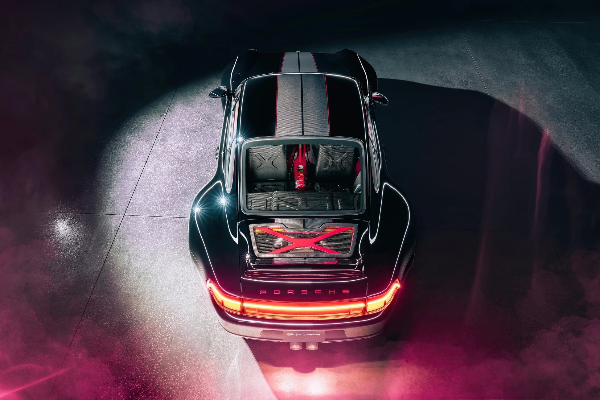 Top view of black Porsche 911 Guntherwerks with red accents and illuminated rear lights in dark setting