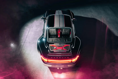 Top view of black Porsche 911 Guntherwerks with red accents and illuminated rear lights in dark setting