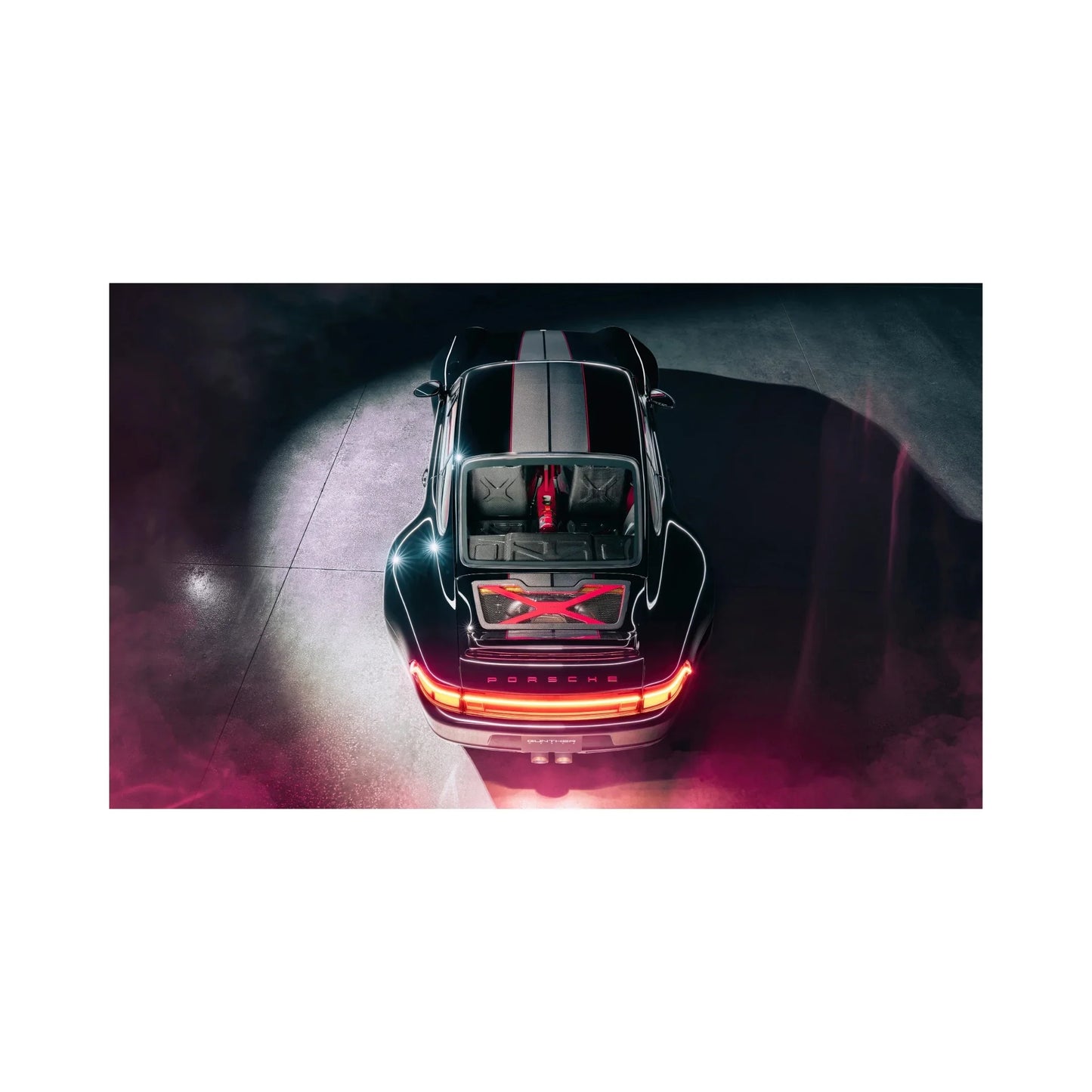 Overhead view of sleek black Porsche sports car with illuminated rear lights and red accents in dark setting